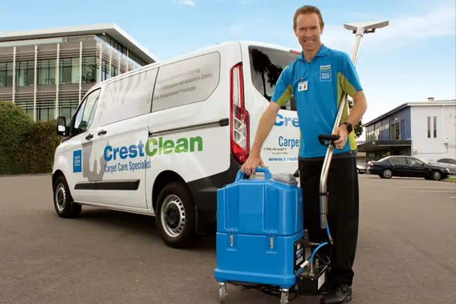 Man with hot water extraction carpet cleaner in front of service van