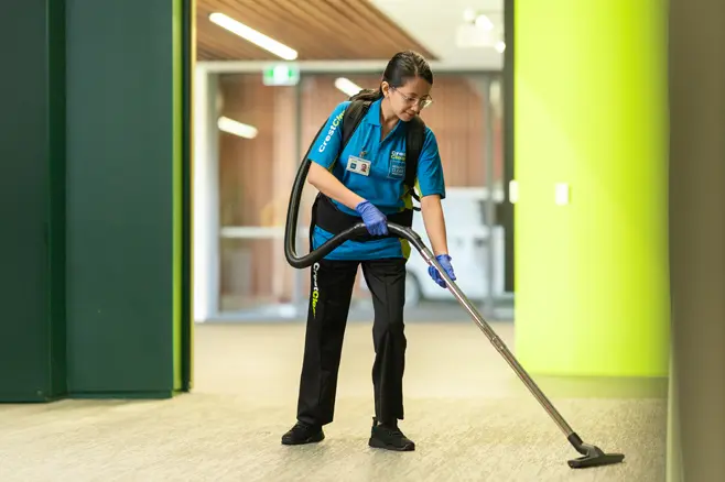 Cleaner in uniform vacuuming corporate office area